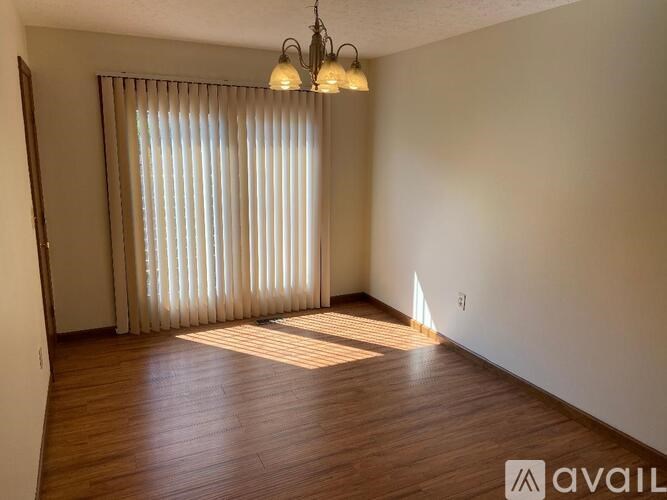 A room with wooden flooring and a window with blinds.