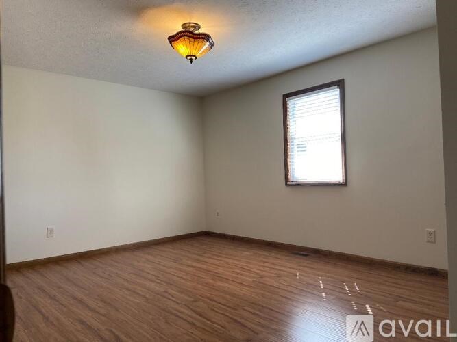 A room with wooden flooring and a window with blinds.