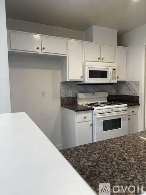 A kitchen with white cabinets and a black countertop.