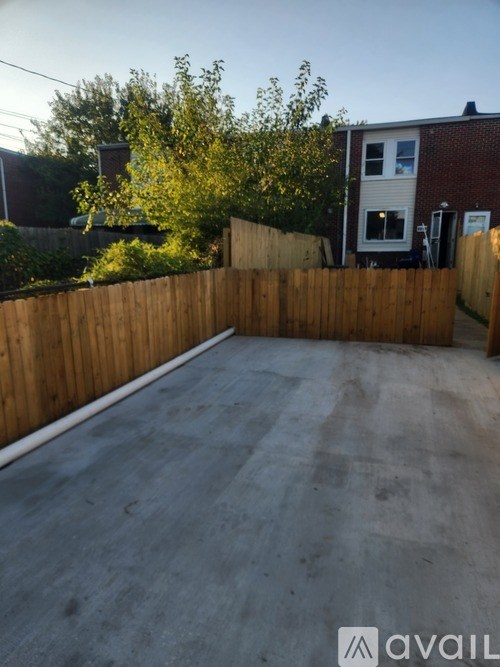 A backyard with a wooden fence and a grey concrete ground.