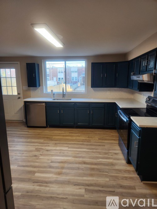 A kitchen with black cabinets and wooden floors.