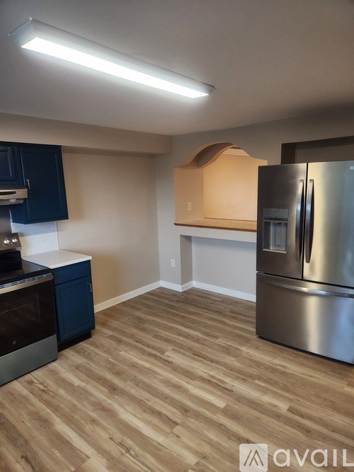 A kitchen with a stainless steel refrigerator and wooden flooring.