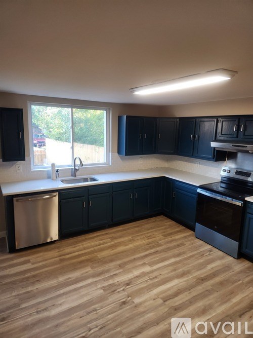A kitchen with black cabinets and a wooden floor.