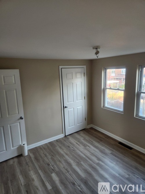 A room with a white door and a window with a view of a building outside.