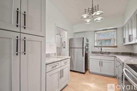 A kitchen with white cabinets and a stainless steel refrigerator.