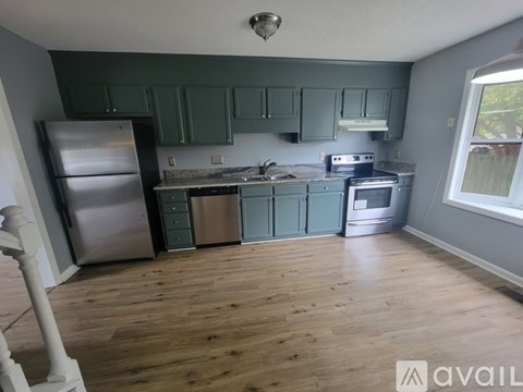 A kitchen with green cabinets and a stainless steel refrigerator.