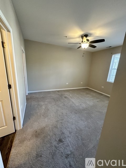 A room with a ceiling fan and carpeted floor.
