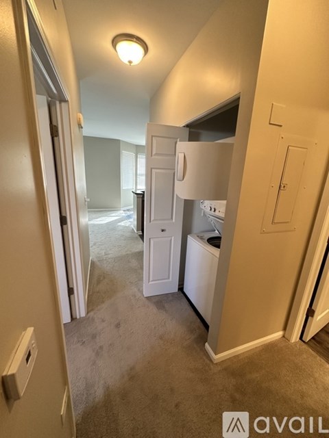 A small, empty room with a white door and a carpeted floor.