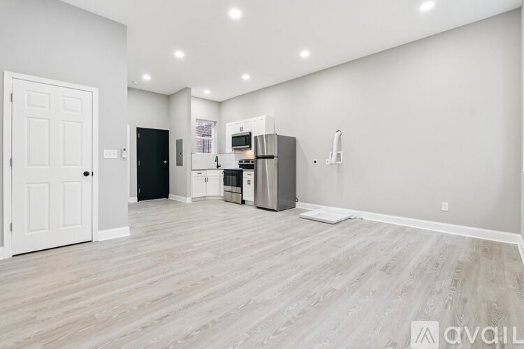 A spacious kitchen with white cabinets and a black refrigerator.