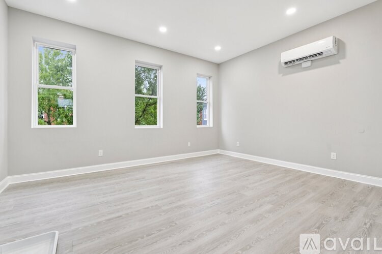 A spacious room with a light-colored floor and two windows.