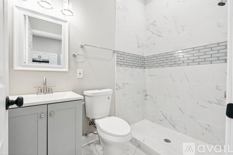 A white toilet sits in a bathroom with marble tile walls.