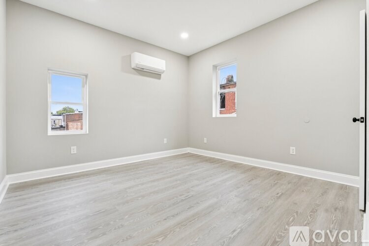 A spacious room with a window and a wall-mounted air conditioner unit.