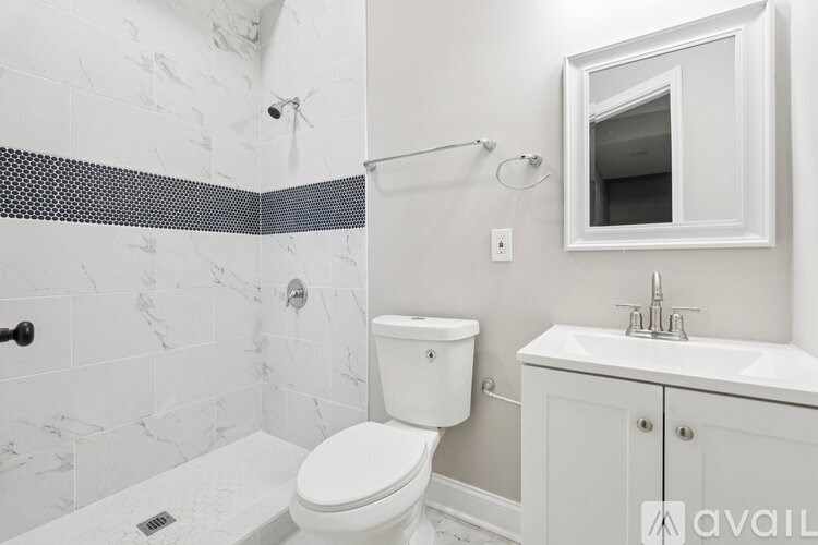 A white toilet sits in a bathroom with a marble tile wall.