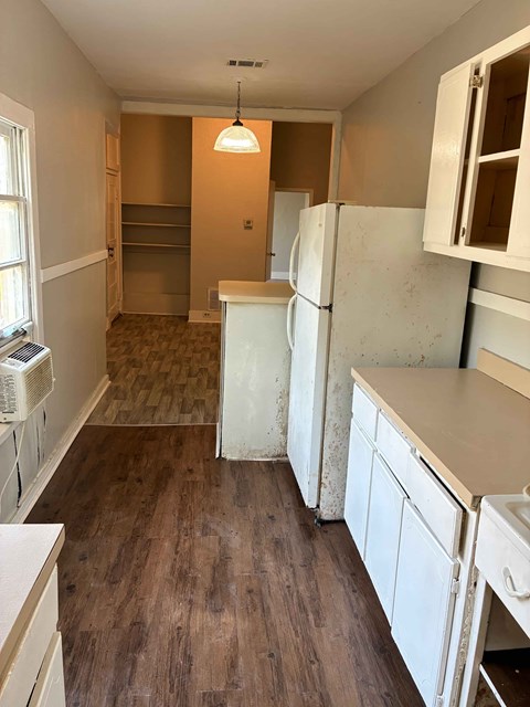 A kitchen with white cabinets and a wooden floor.
