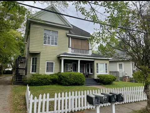 A two-story house with a white picket fence in front.
