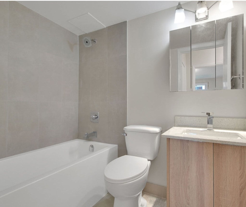 A white toilet sits next to a white bathtub in a bathroom.