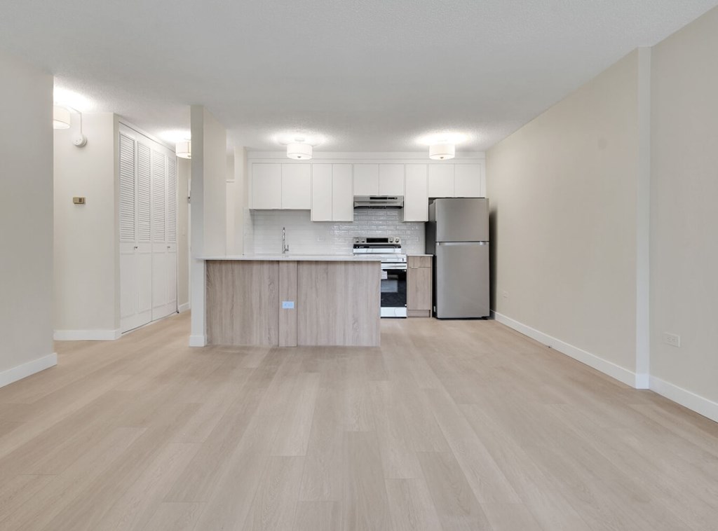 A kitchen with a refrigerator, cabinets, and a countertop.