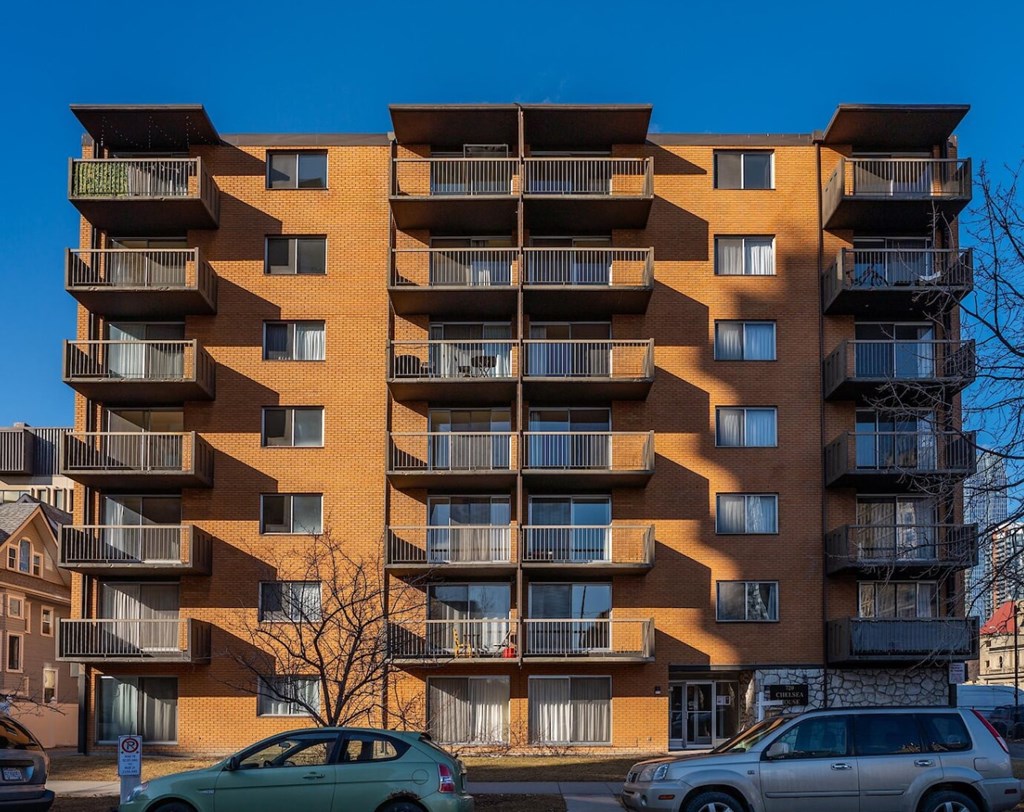 A large apartment building with a tree in front of it.