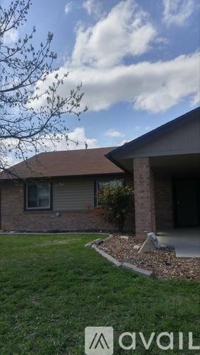 A house with a brown roof and a tree in front of it.