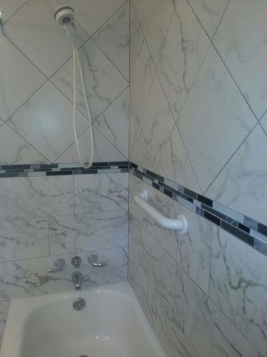 A white bathtub with a shower head and a white shower hose.