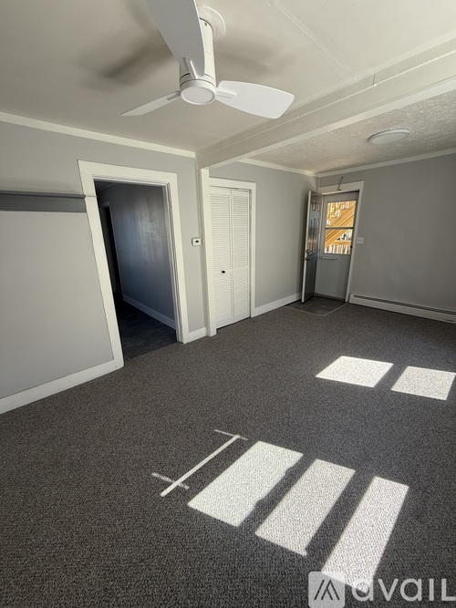 A room with a carpeted floor and a window with blinds.