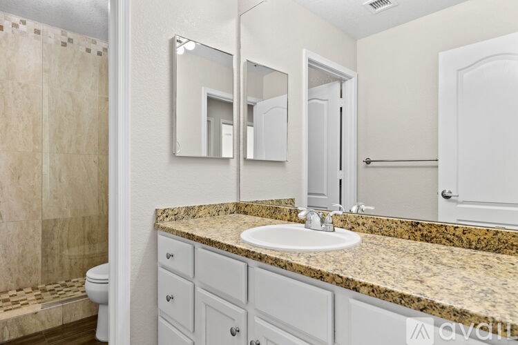 A bathroom with a marble countertop and white fixtures.