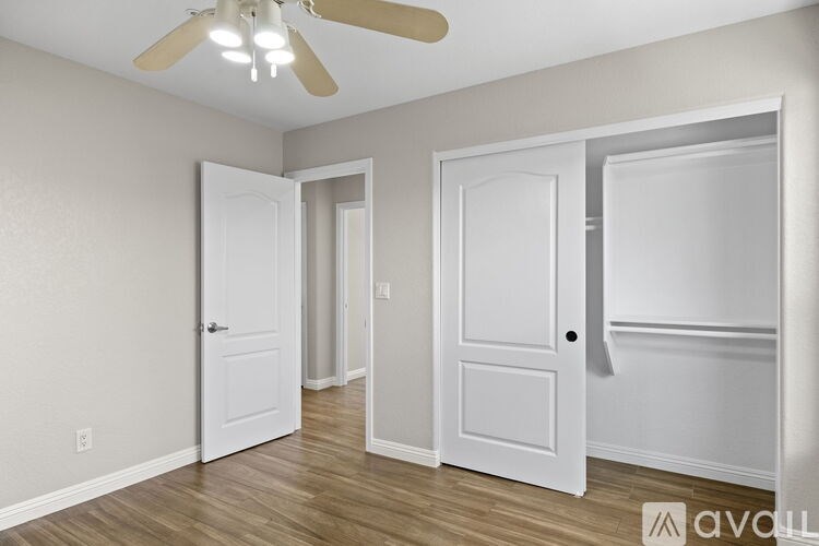 A room with a ceiling fan and three doors.