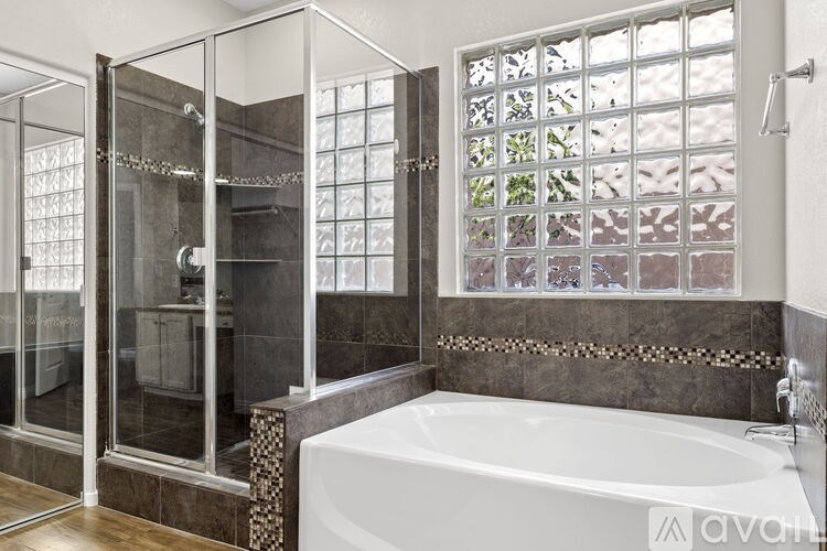 A bathroom with a glass shower stall and a bathtub.