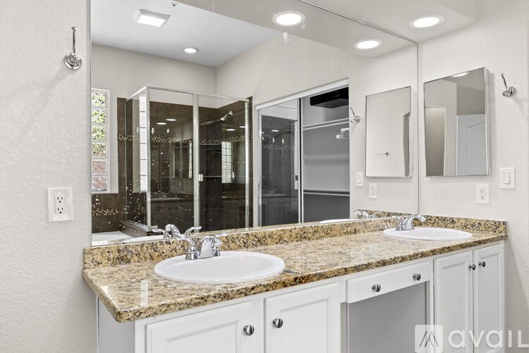 A bathroom with a granite countertop and a large mirror.