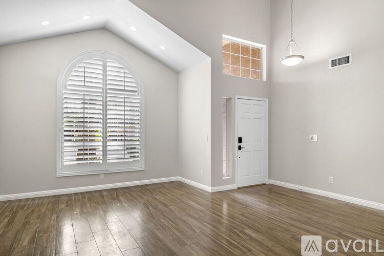 A room with a wooden floor and a window with white blinds.