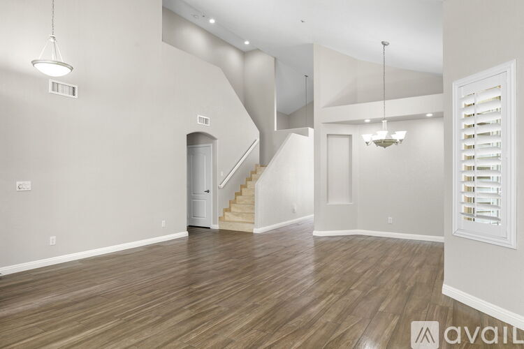A spacious room with wooden flooring and a staircase.