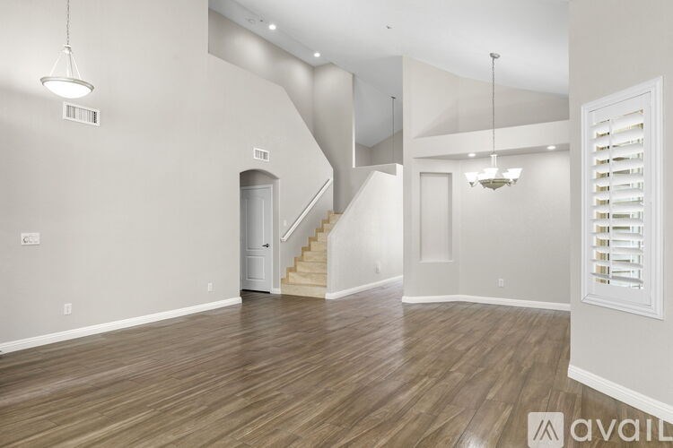 A spacious room with wooden flooring and a staircase.