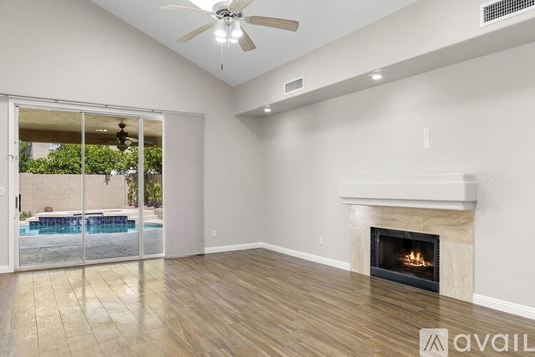 A spacious room with a fireplace and sliding glass doors leading to a pool area.