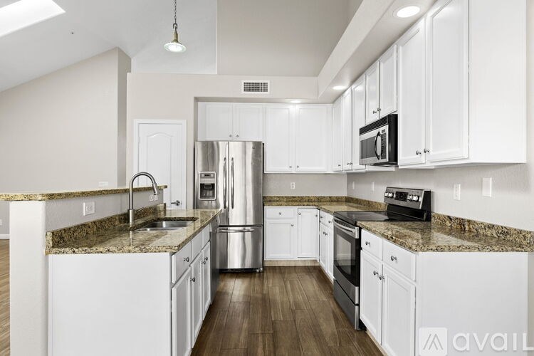 A kitchen with white cabinets and a granite countertop.
