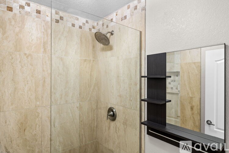 A bathroom with beige tiles and a black shelf.