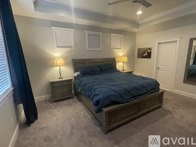 A bedroom with a bed, two lamps, and a ceiling fan.