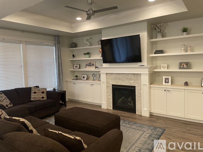 A living room with a fireplace and a television mounted above it.