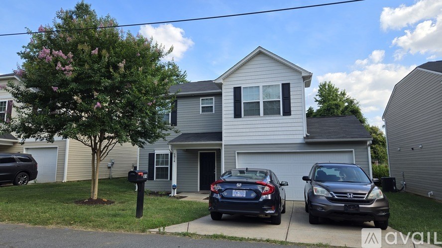 A house with a tree and two cars parked in front.