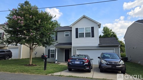 A house with a tree and two cars parked in front.
