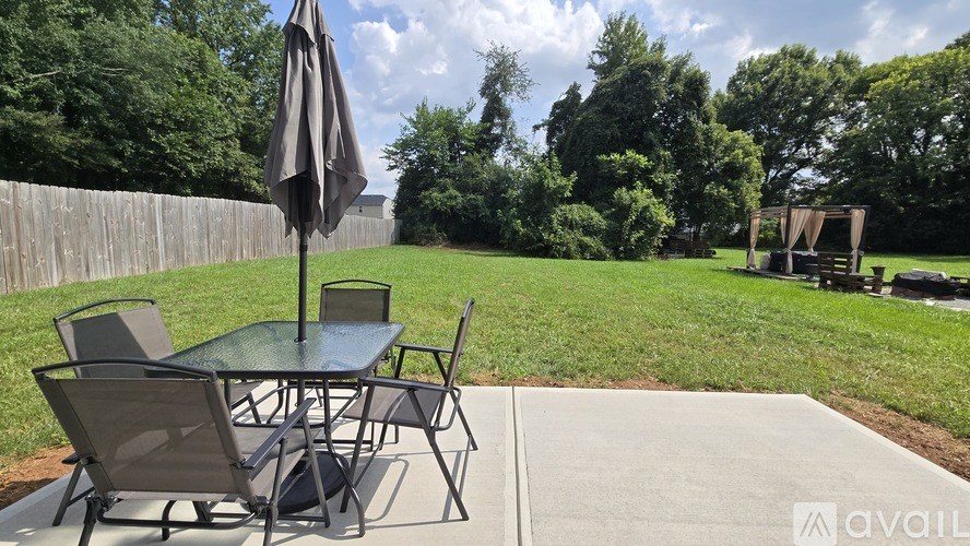 A patio table with chairs and an umbrella is set up on a concrete slab.