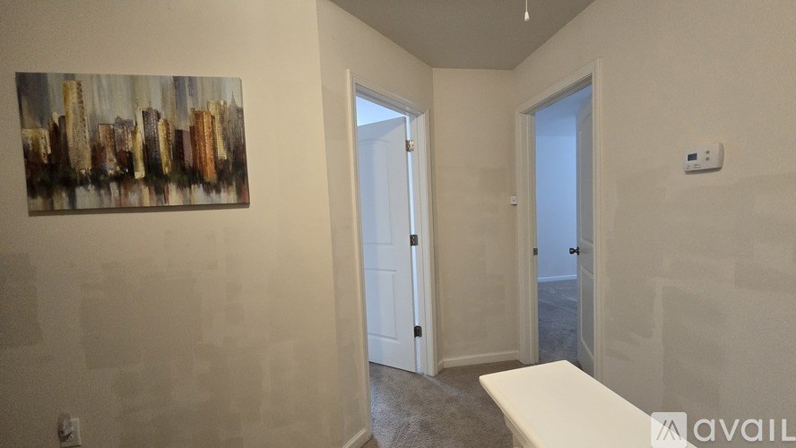 A room with a painting on the wall and a door leading to another room.