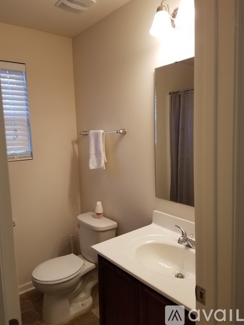A bathroom with a toilet, sink and mirror.