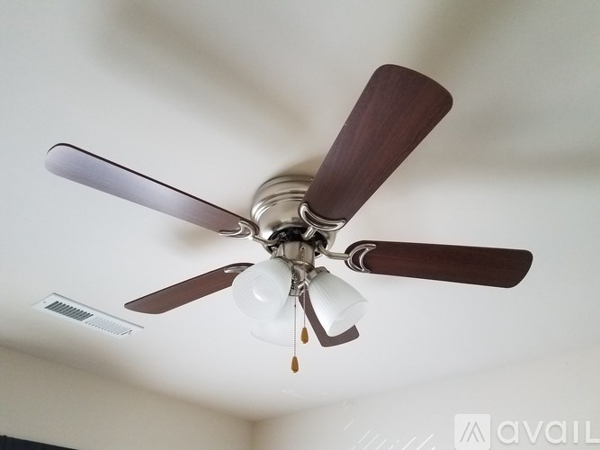 A ceiling fan with brown blades and a light fixture.
