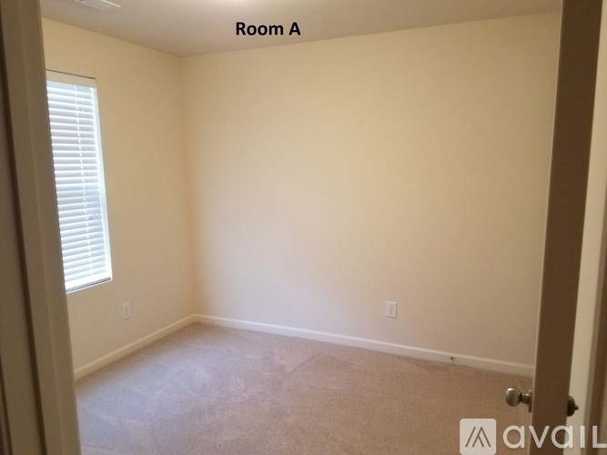 A room with a carpeted floor and a window with blinds.