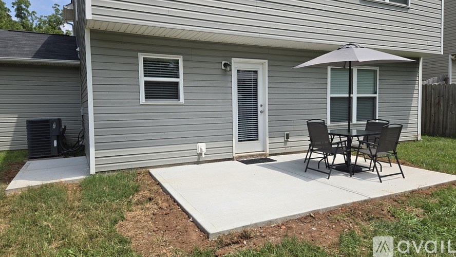 A patio with a table and chairs is in front of a house.