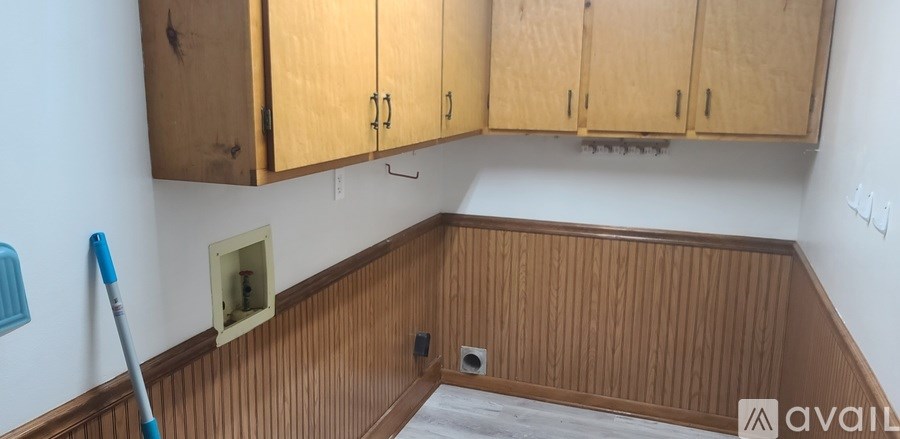 A room with wooden cabinets and a mop on the floor.