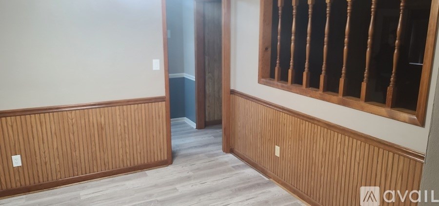 A room with wooden paneling on the walls and a window with wooden bars.