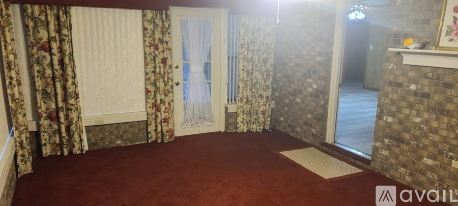 A room with a red carpet and a door with a white curtain.