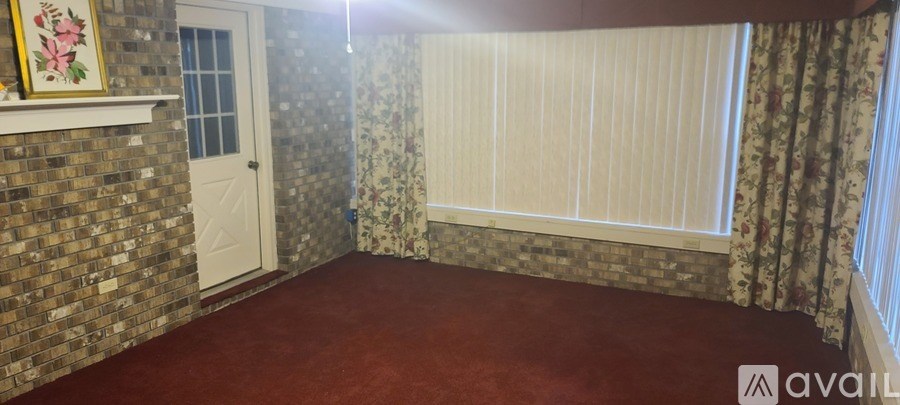 A room with a red carpet and a window with curtains.