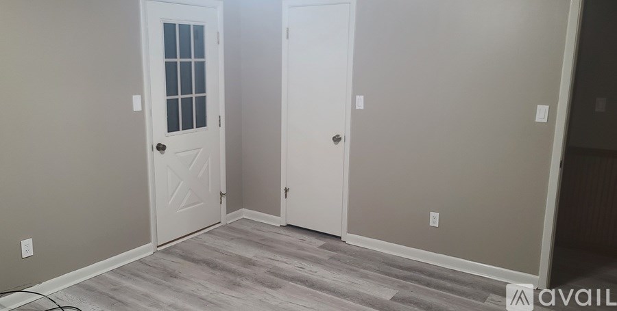 A room with a white door and a grey floor.
